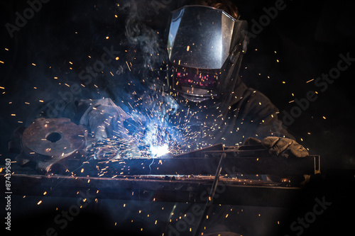 Welder in action with bright sparks. Construction and manufacturing theme.