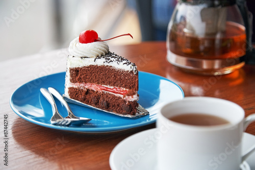 slice of chocolate cake with white icing and cherry
