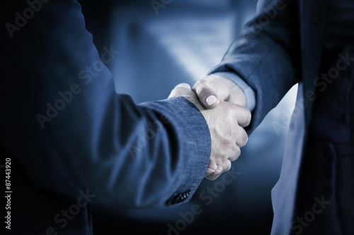 Composite image of business people shaking hands close up