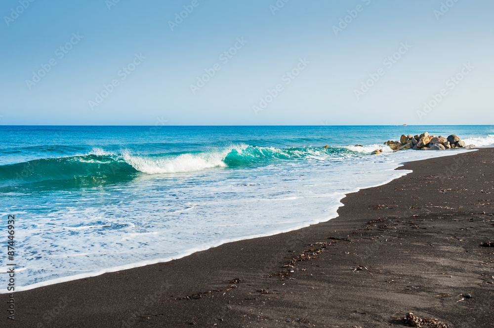 Beautiful beach with turquoise water and black sand.
