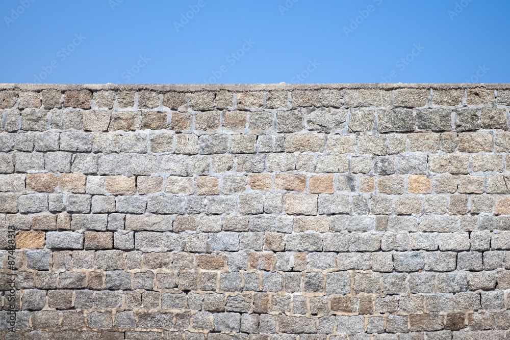 Fototapeta premium Old gray stone wall and blue sky