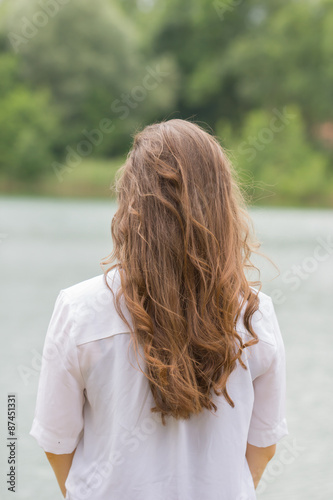 Junge Frau mit langen Haaren schaut nachdenklich auf den See, anonym,  