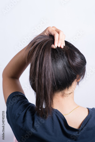 Asian woman braiding hair.