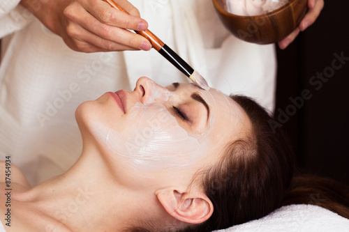 Fotografie Spa treatment. Beautiful woman with facial mask at beauty salon.