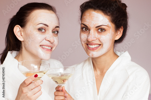 Smiling girlfriends with champagne in the spa