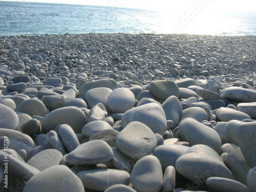Closeup of white pebbles on the beach on a late sunny afternoon, low angle perspective.