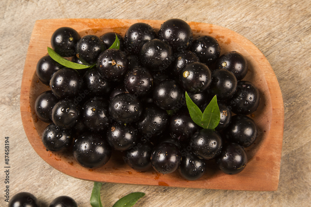 Berry Jaboticaba in bowl on wooden table Berry Jaboticaba in bowl on wooden table