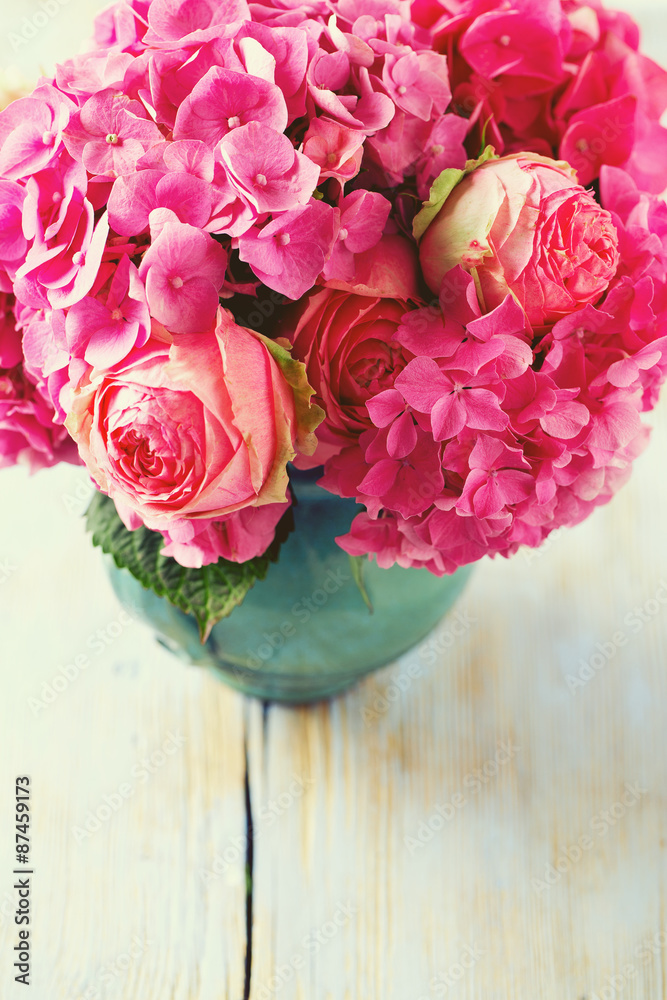 beautiful pink roses and hydrangea in vase on wooden table