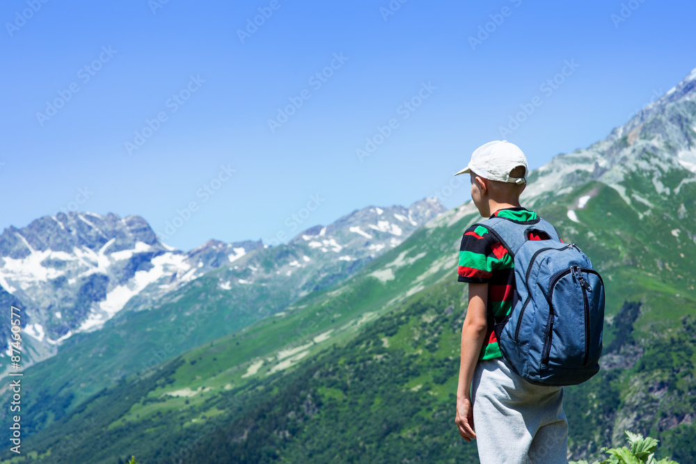 Boy with a backpack looking at the mountain