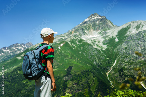 Boy with a backpack looking at the mountain