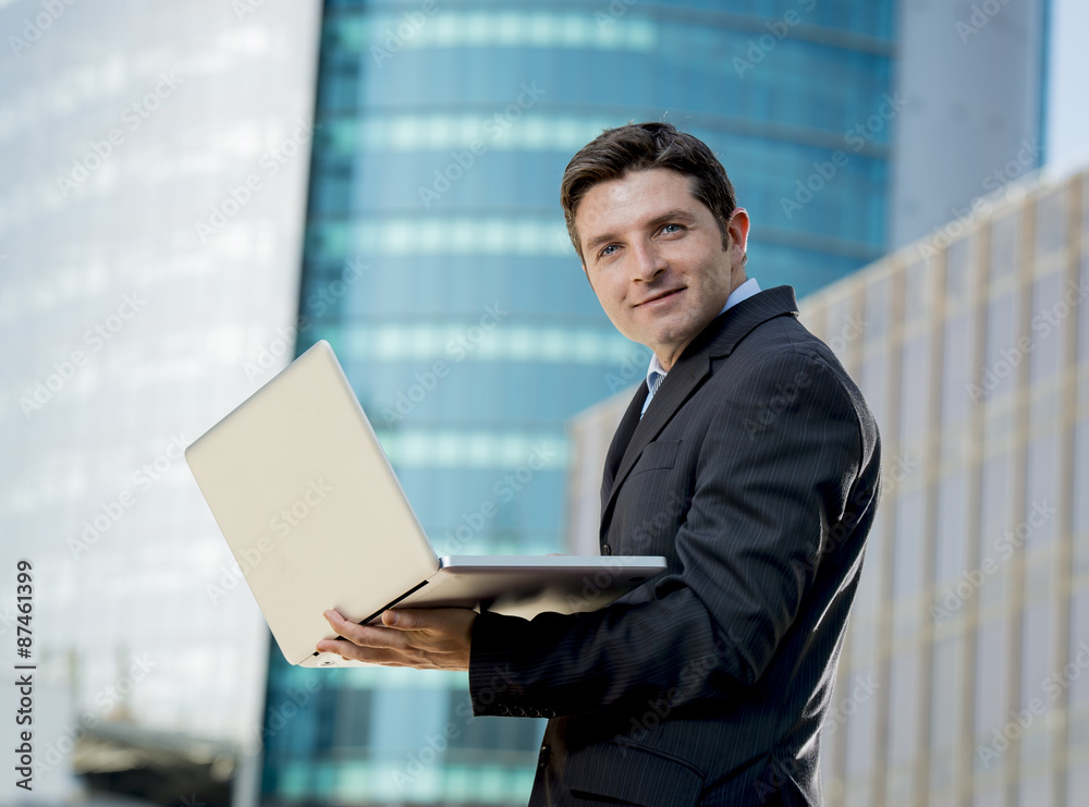 young businessman holding computer laptop working urban outdoors