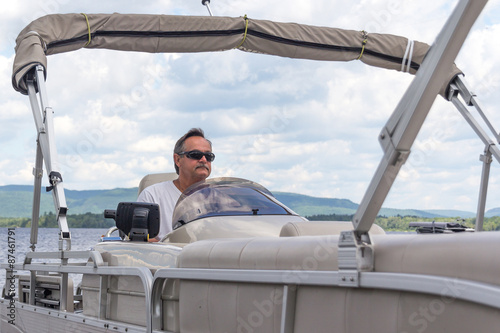 mature men driving a pontoon boat on a lake photo