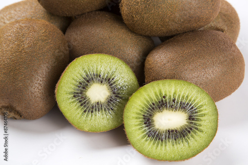 Some kiwis in a basket over a wooden surface