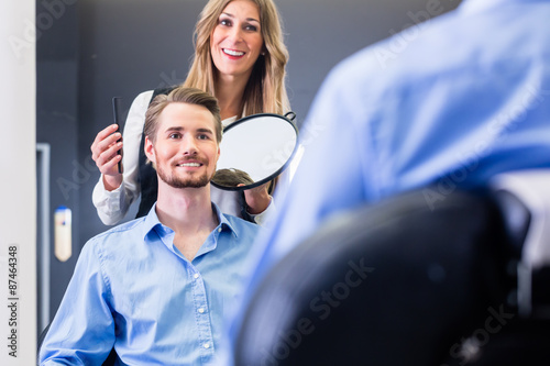 Friseur gibt Kunde Haarschnitt im Spiegel photo