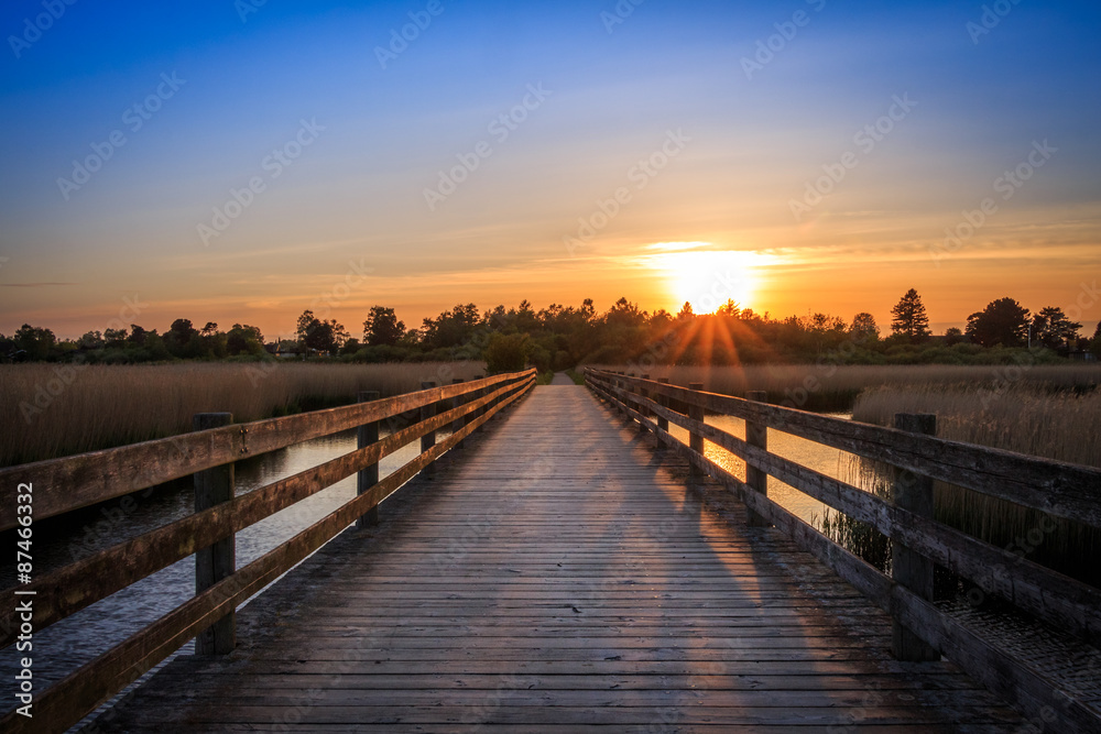 Bridge crossing sea at sunset