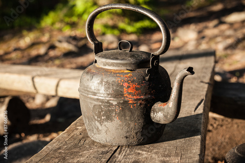 Old kettle in wooden bench outdoors