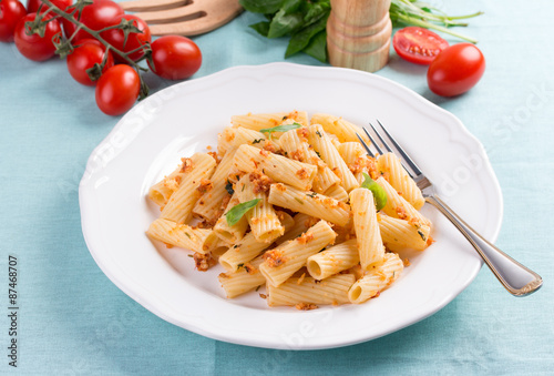 Plate of penne pasta with bread crumbs, basil and cherry