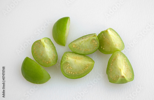 Cut tomatillos on a white cutting board photo