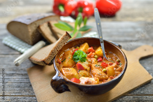 Deftiges, vegetarisches Kartoffelgulasch in der Keramikschale mit Bauernbrot serviert 