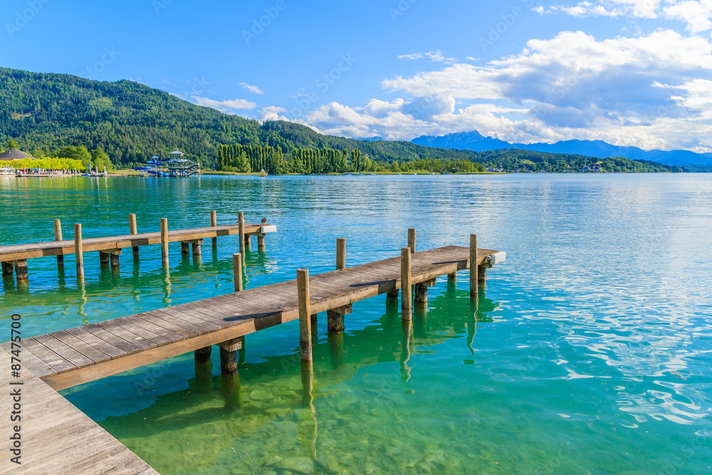 Wooden pier for mooring boats on Worthersee lake on beautiful summer day, Austria
