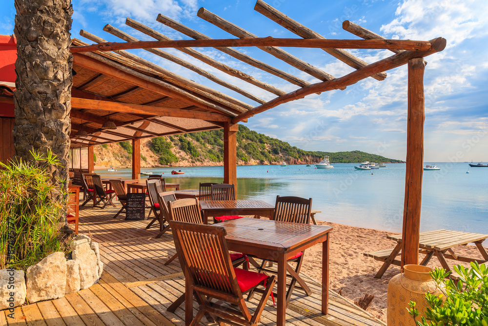 Chairs and tables in beach bar in Santa Manza bay, Corsica island, France