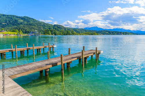 Wooden pier for mooring boats on Worthersee lake on beautiful summer day, Austria