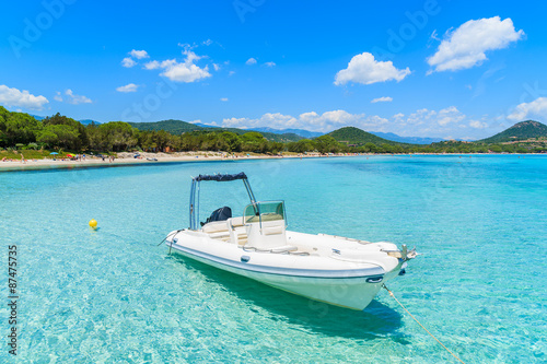 White dinghy boat on crystal clear turquoise sea water of Santa Giulia beach, Corsica island, France