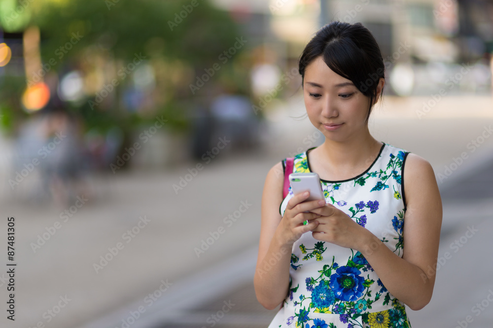 Young Asian woman texting on cell phone