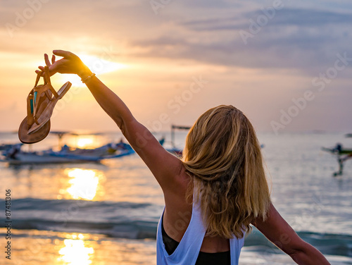 Woman on the beach in Bali Indonesia holding her sandals sunset photo