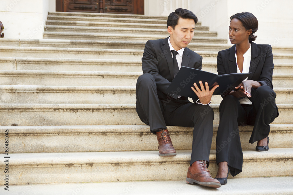 Man shows woman information in a binder. Could be lawyers, lawyer and client, or business people. Man shows woman information in a binder. Could be lawyers, lawyer and client, or business people.