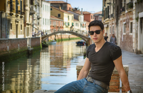 Young Man on Bridge Over Narrow Canal in Venice