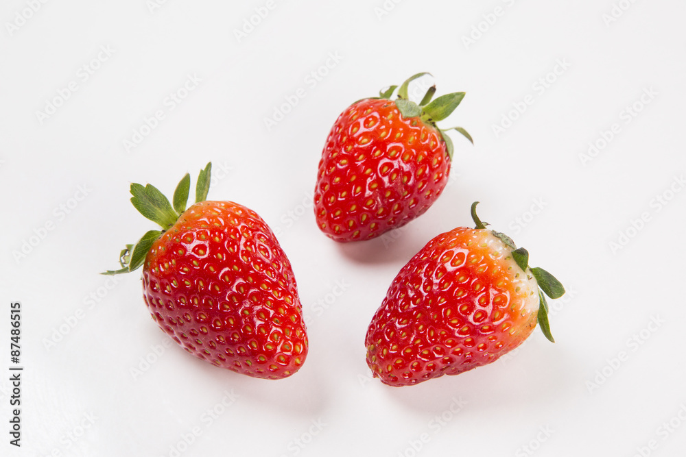 A strawberry cut in a half in front of three entire strawberries A strawberry cut in a half in front of three entire strawberries