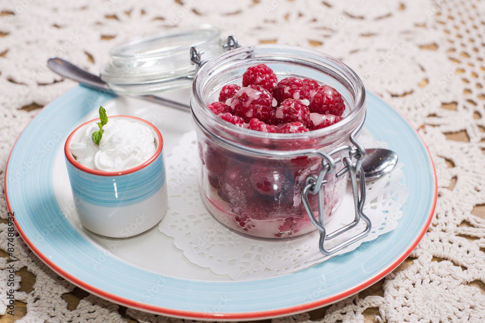 Raspberry dessert. raspberries in small glass jar and whipped cream in a cup Raspberry dessert. raspberries in small glass jar and whipped cream in a cup