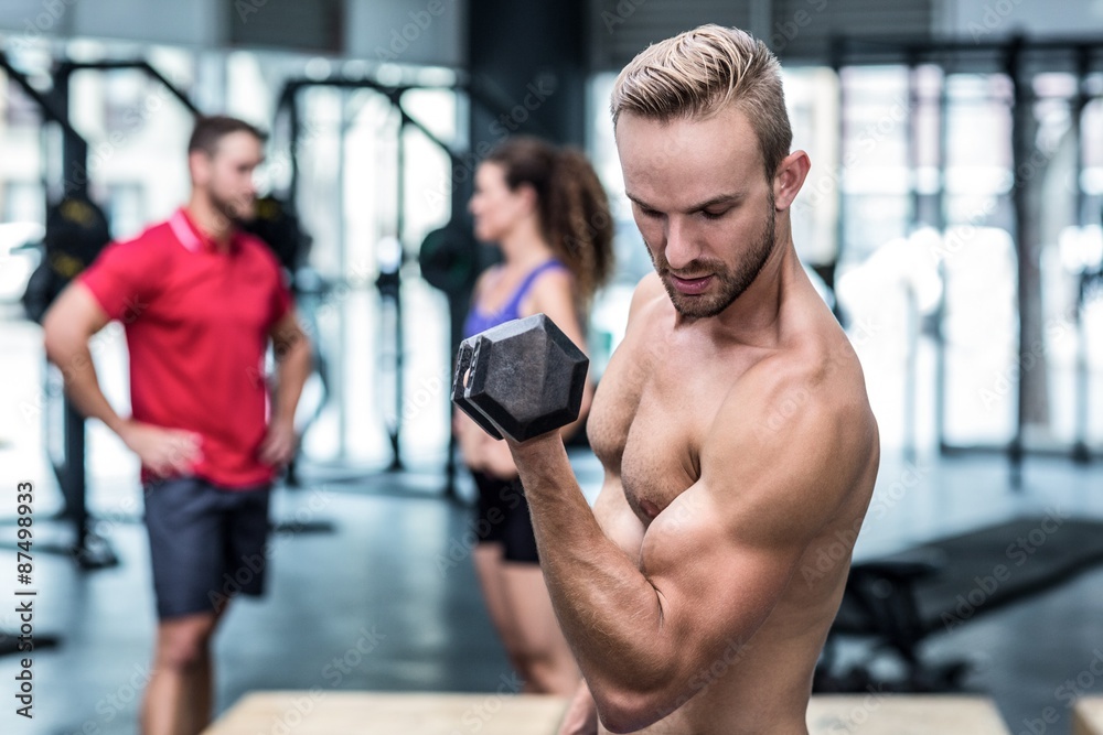Naklejka premium Muscular trainer lifting a dumbbell 