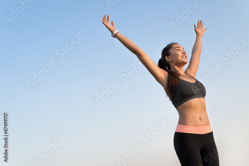 Happy asian woman raising arms to the sky.