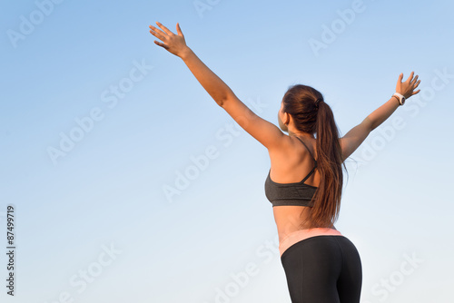 Woman is back raising arms to the sky.