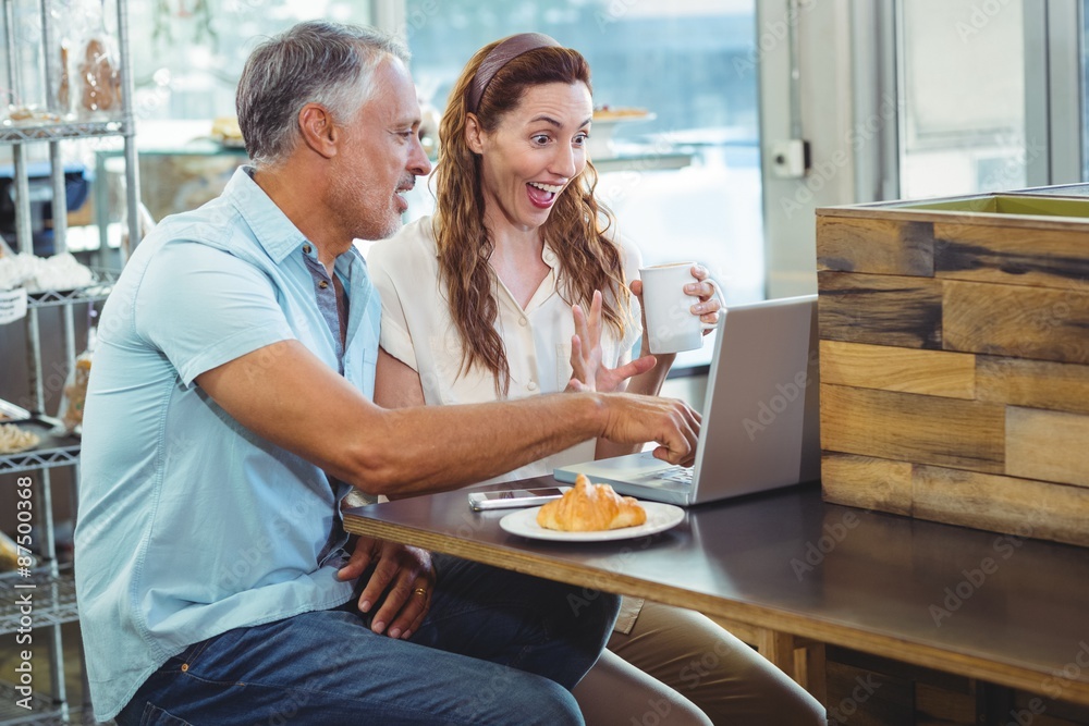 Fototapeta premium Happy couple watching something funny on laptop