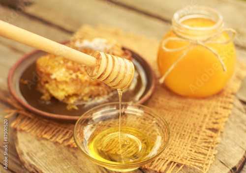 Honey in jar with honeycomb and wooden background.