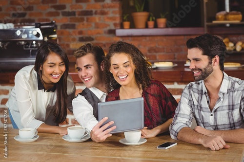 Smiling friends looking at digital tablet 