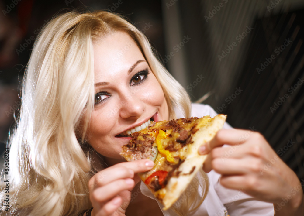 Attractive blond girl eating pizza