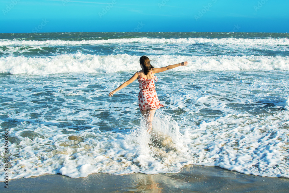Woman running in waves of an ocean at the beach