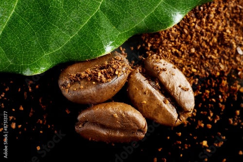 Closeup shot of coffee powder,beans with green leaf on black
