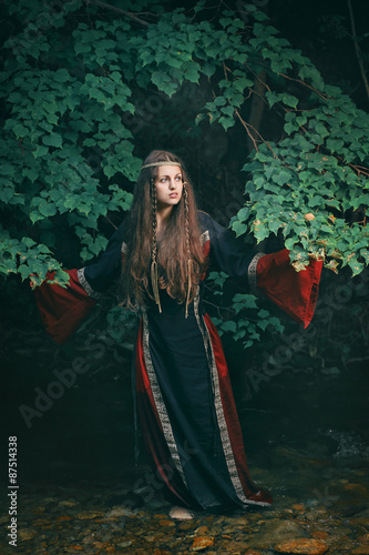 Beautiful medieval woman in a forest stream