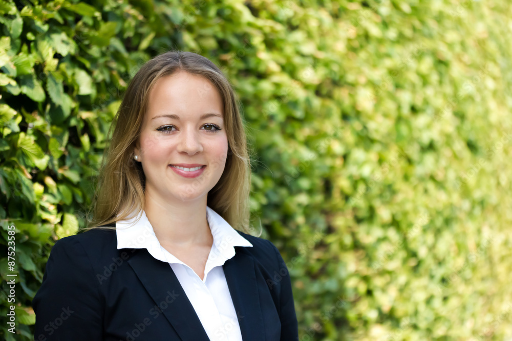 junge blonde Geschäftsfrau steht vor einem grünen Hintergrund junge blonde Geschäftsfrau steht vor einem grünen Hintergrund
