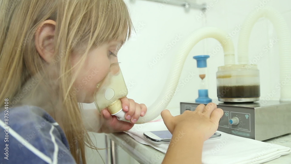The girl is treated, making inhalation at the hospital, wearing face mask
