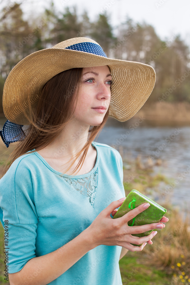 Fototapeta premium Freckled girl in hat standing with note and looking away