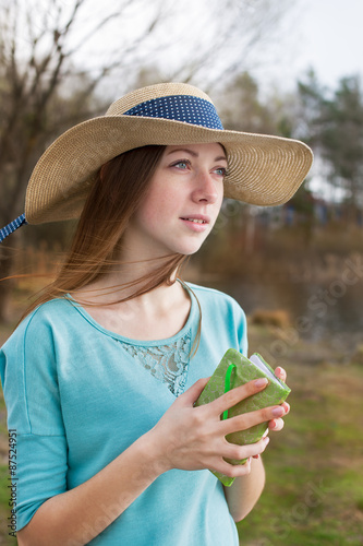 Freckled girl in hat standing with note and looking away