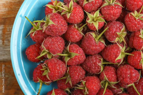 Red raspberry in blue dish on old vintage wooden table.