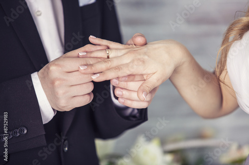 Hands of the groom and bride is wearing a ring on the finger on