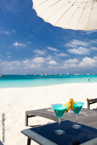 Blue Curacao cocktail with slice of pineapple on white beach photo